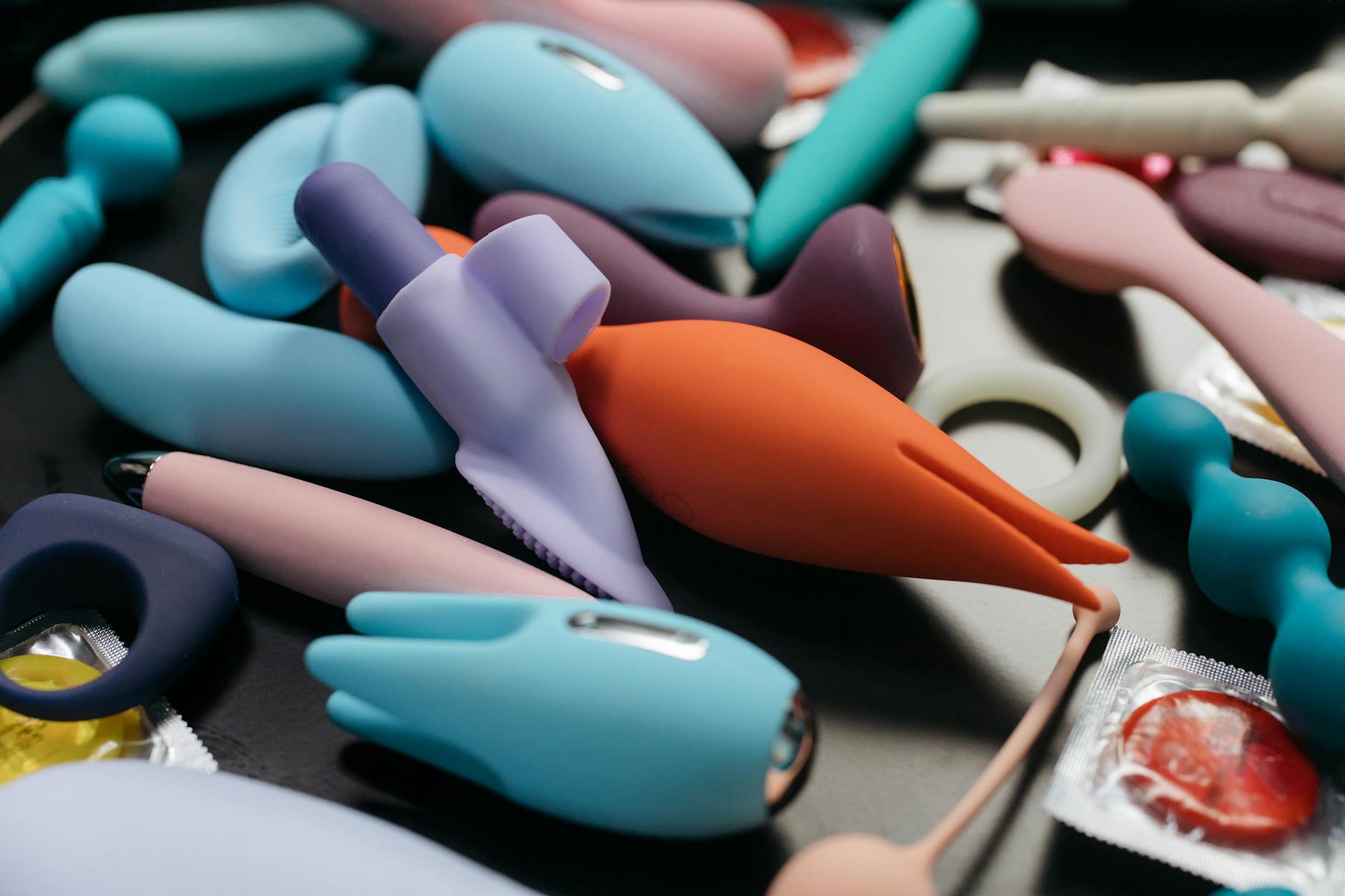 Woman holding blue and pink vibrators, considering how to share with partner