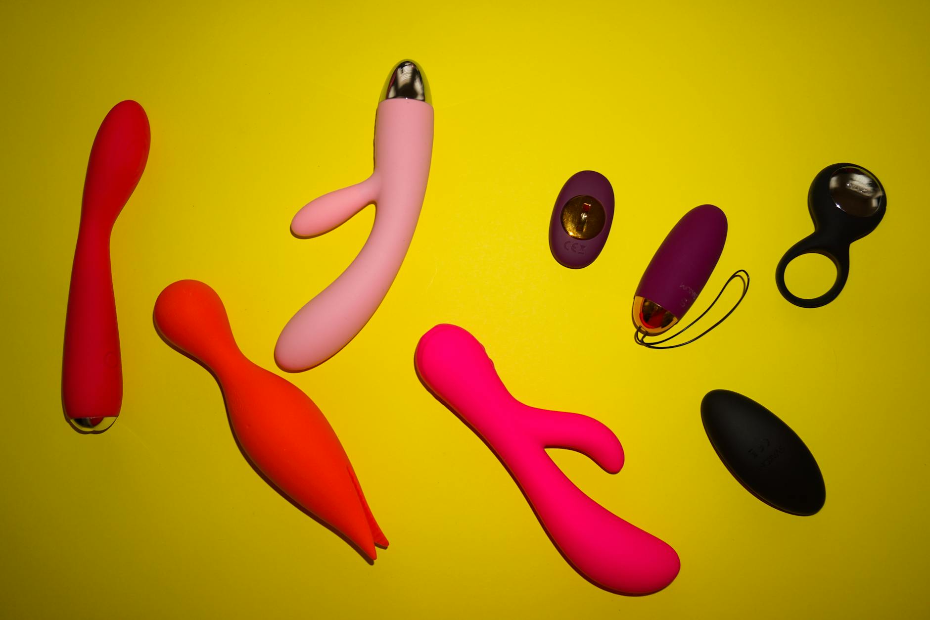 Colorful vibrators arranged on a bright yellow background showcasing different designs