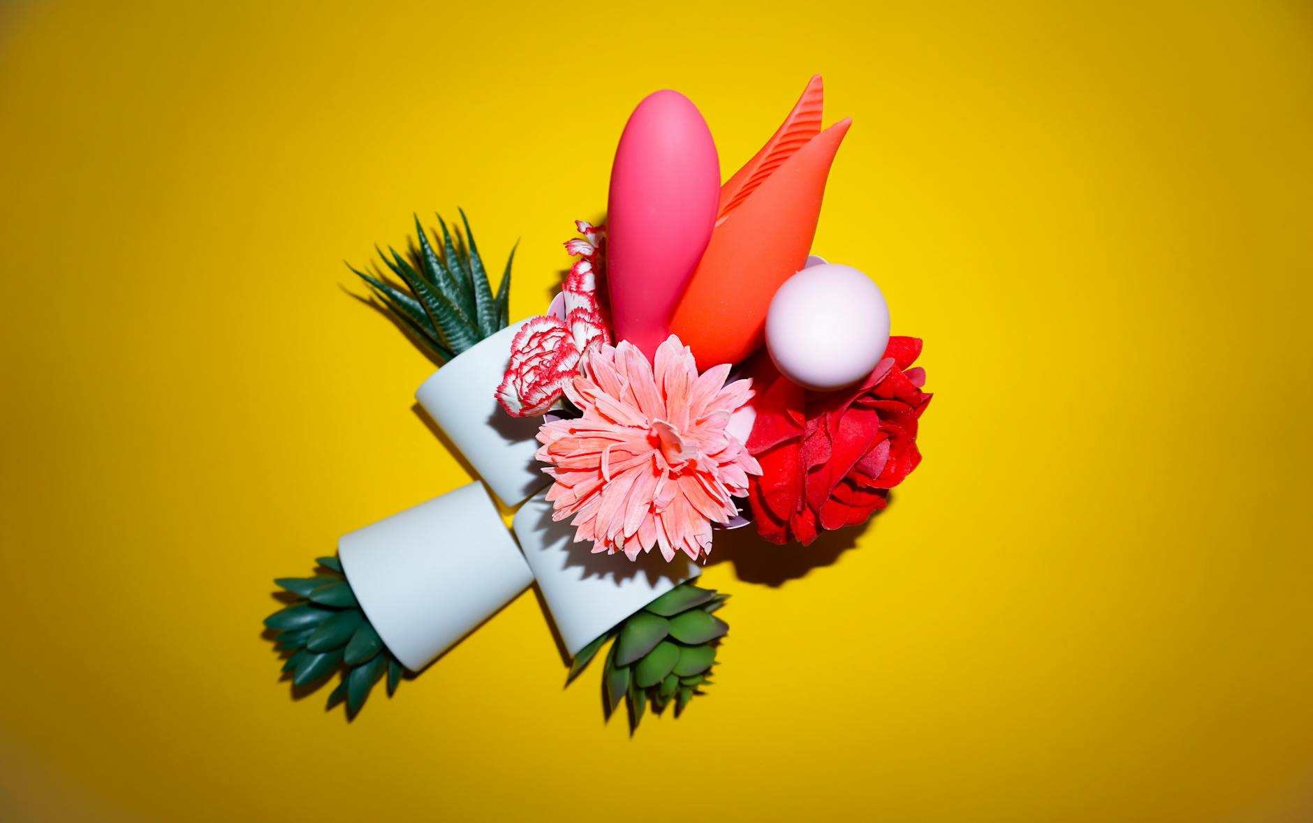 Two hands holding pink and blue silicone lemon vibrators against a pastel background