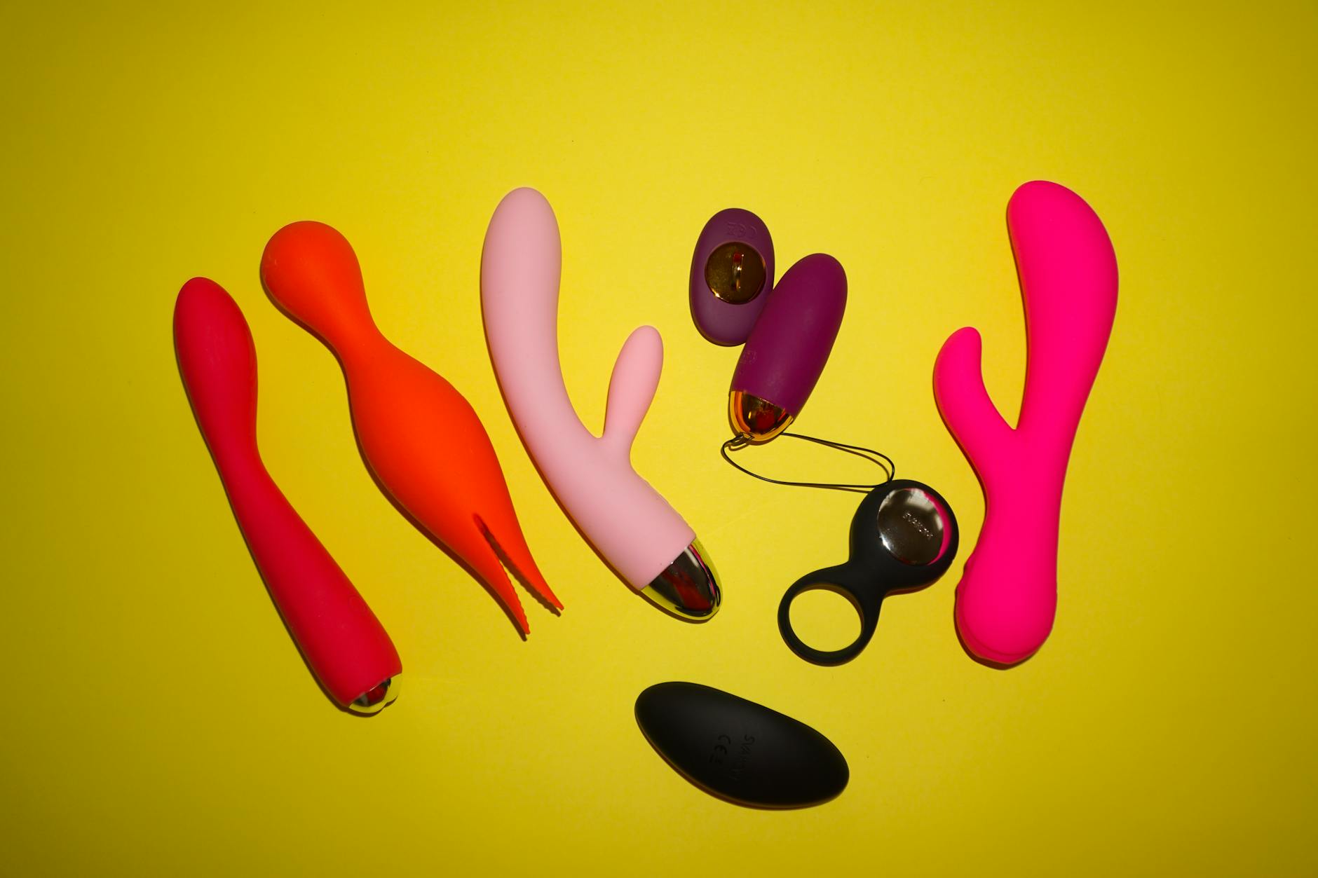 Woman holding two colorful vibrators thoughtfully against a purple background